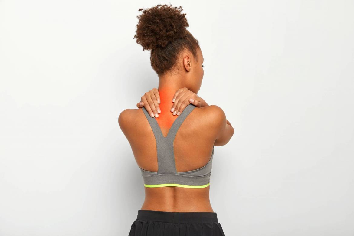 curly-haired-young-afro-woman-massages-tense-muscles-has-pain-in-neck-and-spasm-dark-skin-wears-sport-bra-isolated-over-white-background-1-scaled.jpg